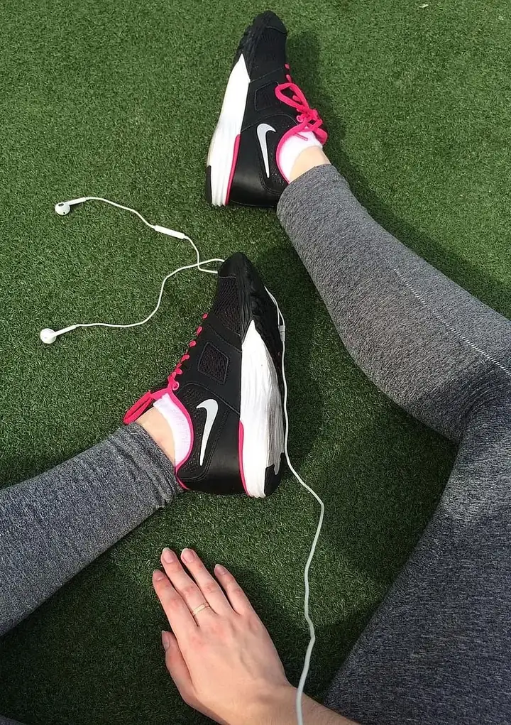 Person wearing training shoes with earphones on the grass